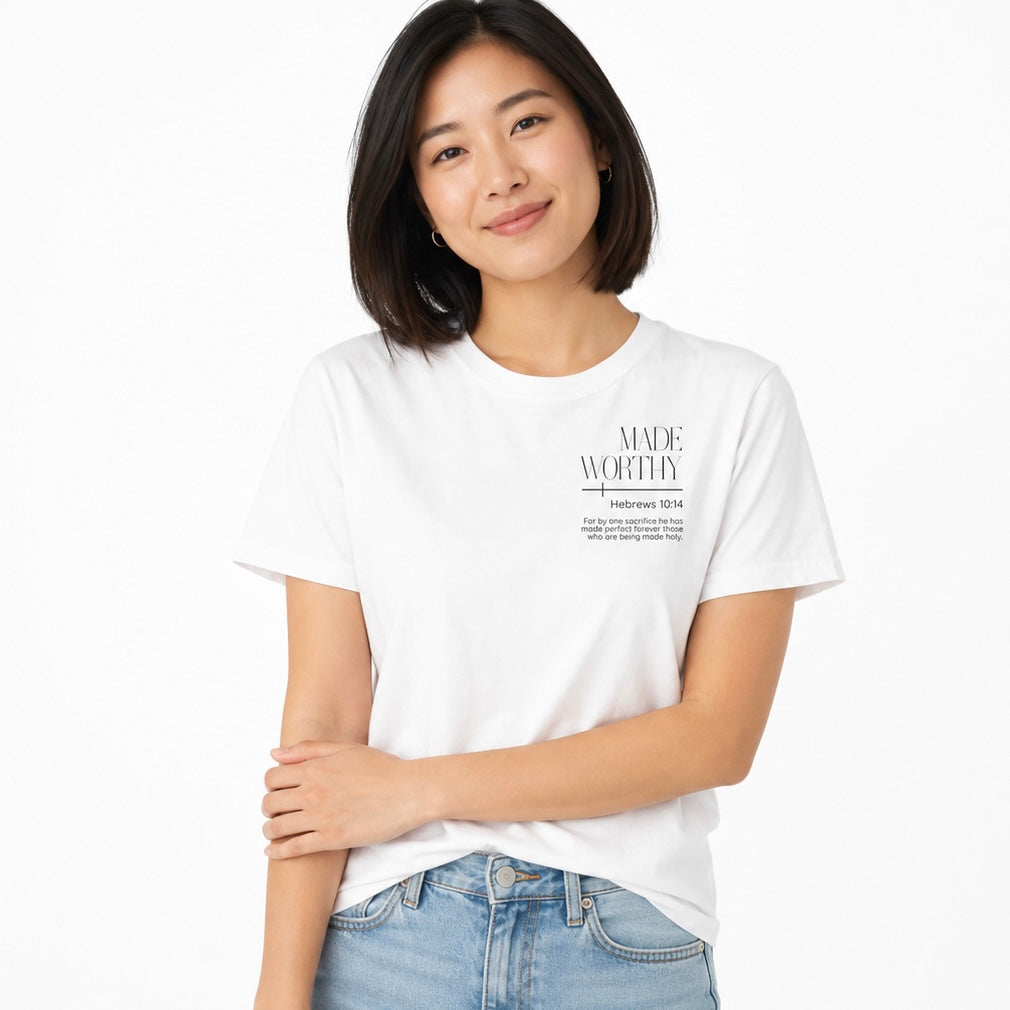 Woman wearing a white t shirt with black writing that says ‘Made Worthy’ and scripture from Hebrews 10:14 on it with a white background.