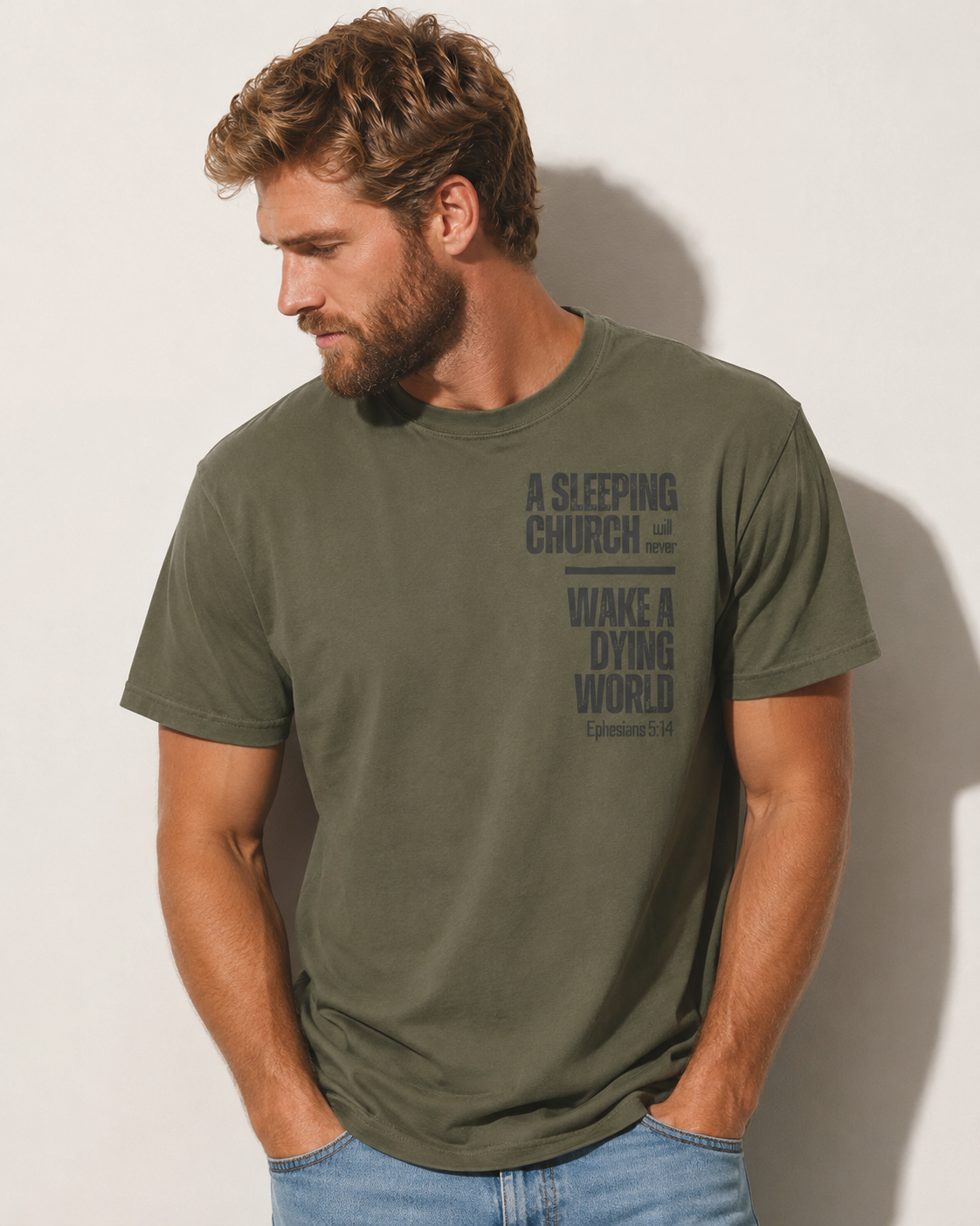 Man wearing a sage green Ephesians 5:14 Christian T-shirt featuring the words “A sleeping church will never wake a dying world.”