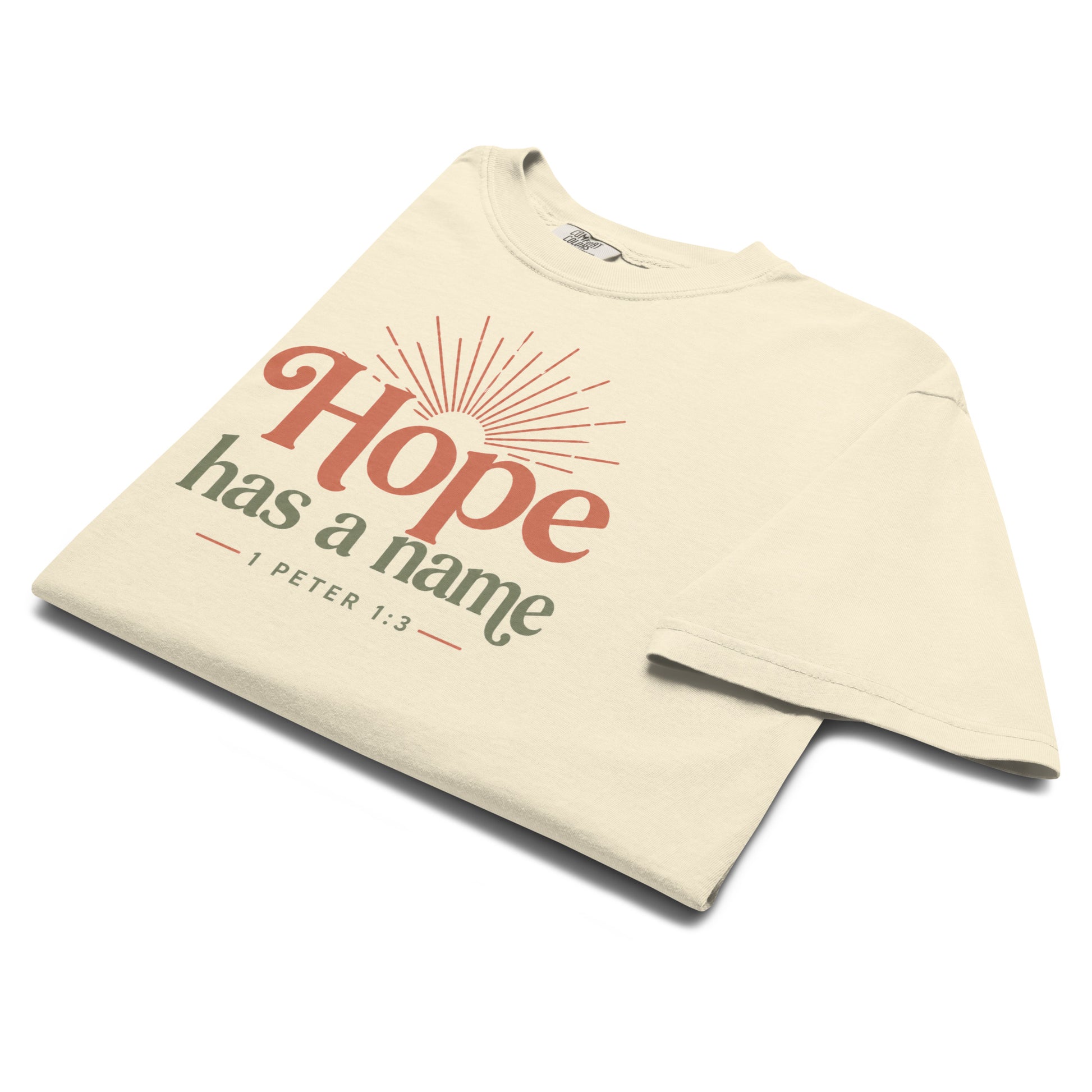 Folded ivory Hope Has a Name Christian T-shirt with rust and olive 1 Peter 1:3 sunrise design