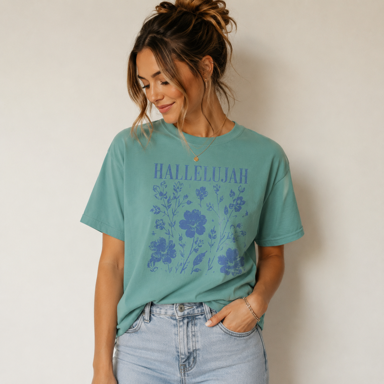 Woman wearing a seafoam Hallelujah Christian floral T-shirt with light-wash jeans