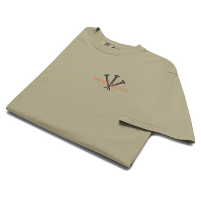 Folded khaki Known Society Christian T-shirt showing the three-nail chest graphic and Isaiah 43:1 detail.