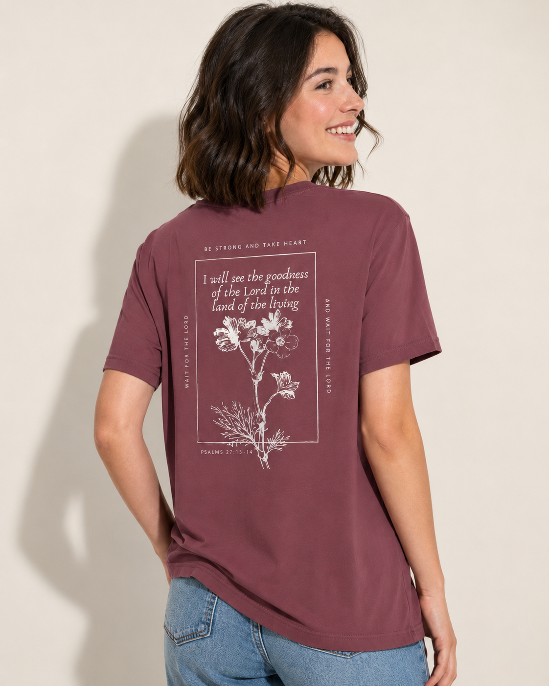 Woman modeling the Brick Psalm 27 scripture tee with a floral Bible verse design on the back.