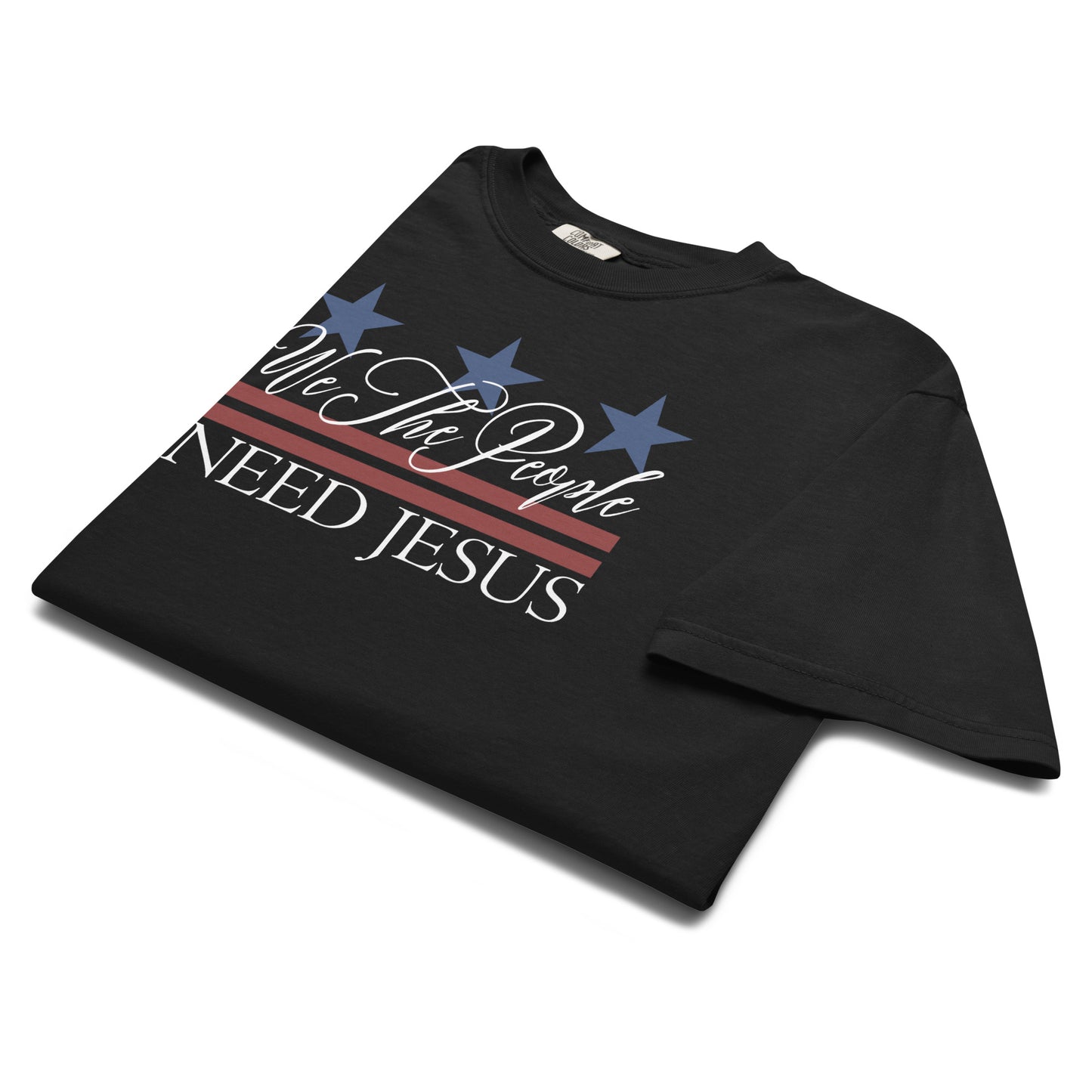 Angled close-up of the patriotic We the People Need Jesus design on a black T-shirt.