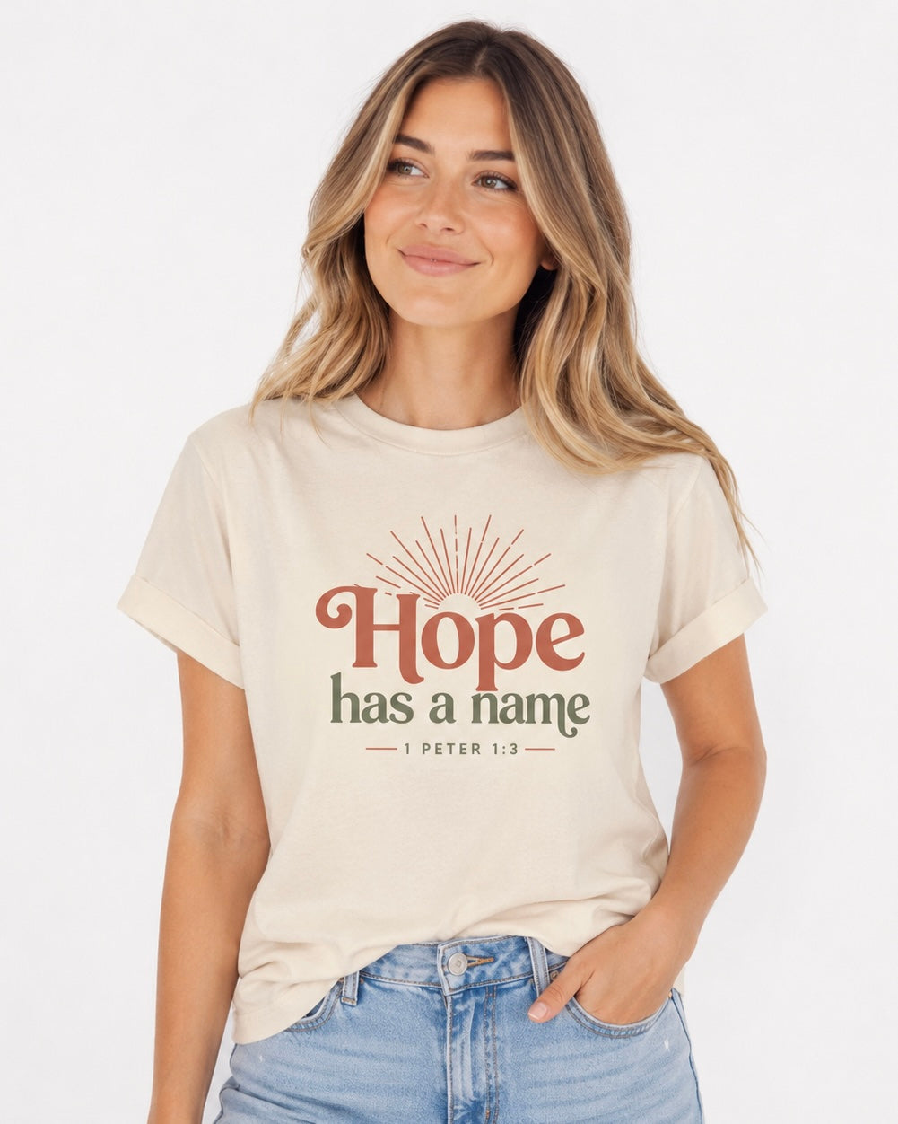 Woman wearing an ivory Hope Has a Name Christian T-shirt with 1 Peter 1:3 graphic and light-wash jeans